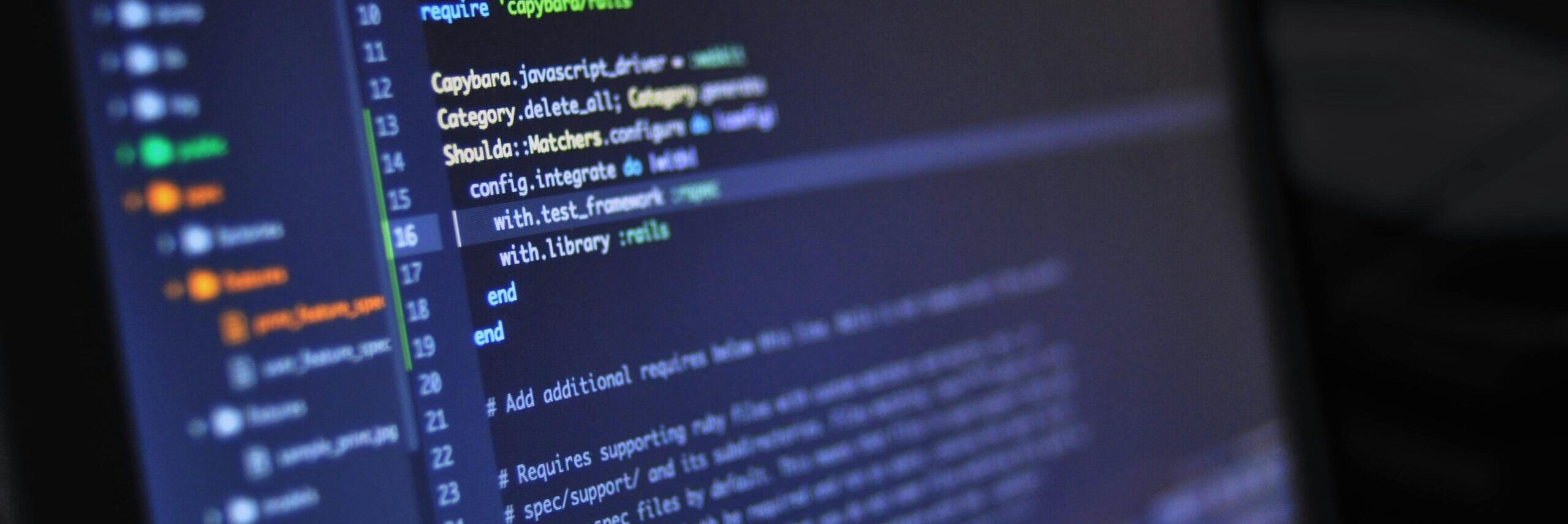 Close-up of a computer screen displaying programming code in a dark environment.